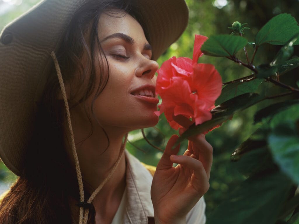 a-woman-wearing-a-hat-is-smelling-a-flower-John-FRANCEY-
