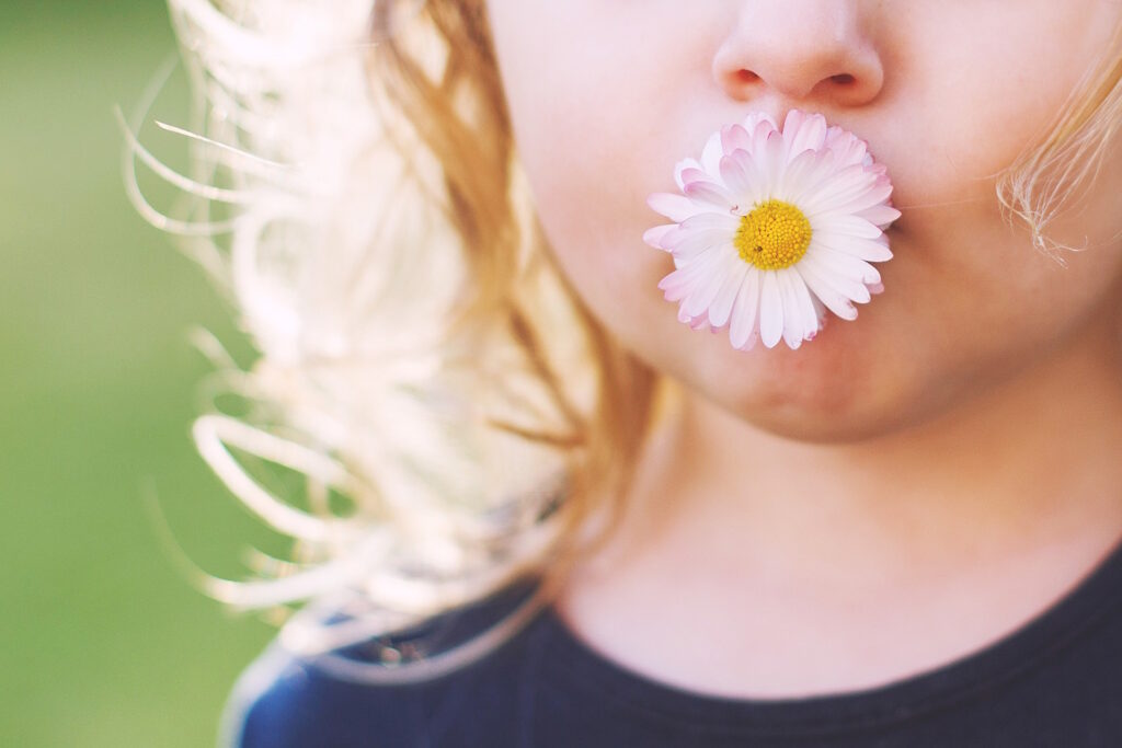 girl-with-a-daisy-flower-in-her-mouth-on-a-green-John-FRANCEY