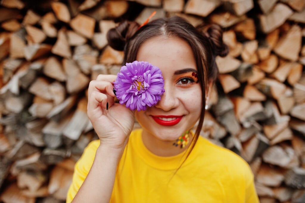 Girl in yellow shirt with violet aster flowers at hand behind eye John FRANCEY